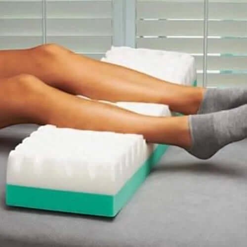 Prevent Products GeriHeel flotation device with white foam and teal base, supporting legs to prevent heel ulcers.